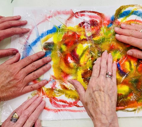 fünf Hände auf einem bunten, selbst gemalten Bild